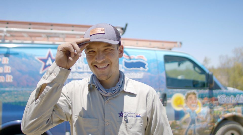 Advantage Air Mechanical HVAC technician wearing a branded shirt smiling in front of a service truck