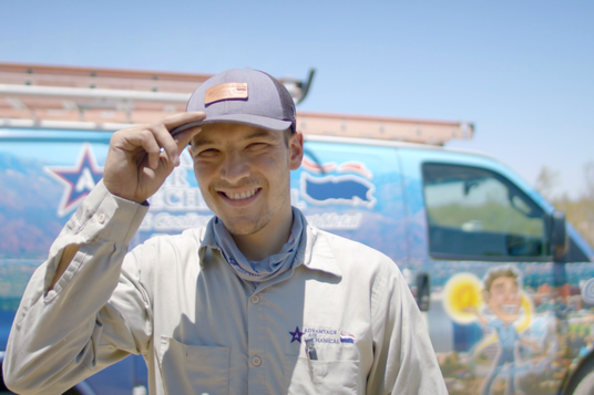 Advantage Air Mechanical HVAC technician wearing a branded shirt smiling in front of a service truck