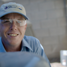 A uniformed Advantage Air tech wearing clear safety glasses smiling at the camera.