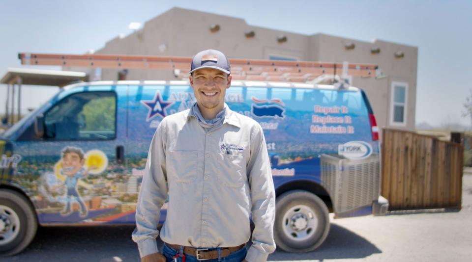 A uniformed Advantage Air tech standing in front of a branded service van smiling at the camera