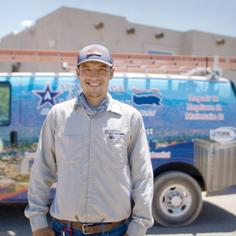 A uniformed Advantage Air tech standing in front of a branded service van smiling at the camera