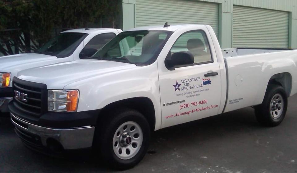 Two branded service trucks parked next to each other outside of a warehouse.