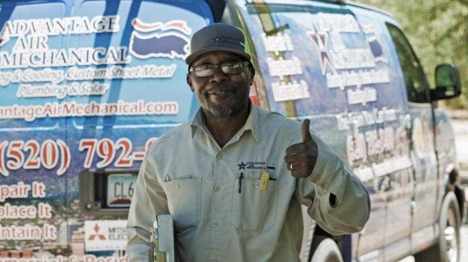 A uniformed Advantage Air technician standing behind a branded service van smiling and giving a thumbs up to the camera.