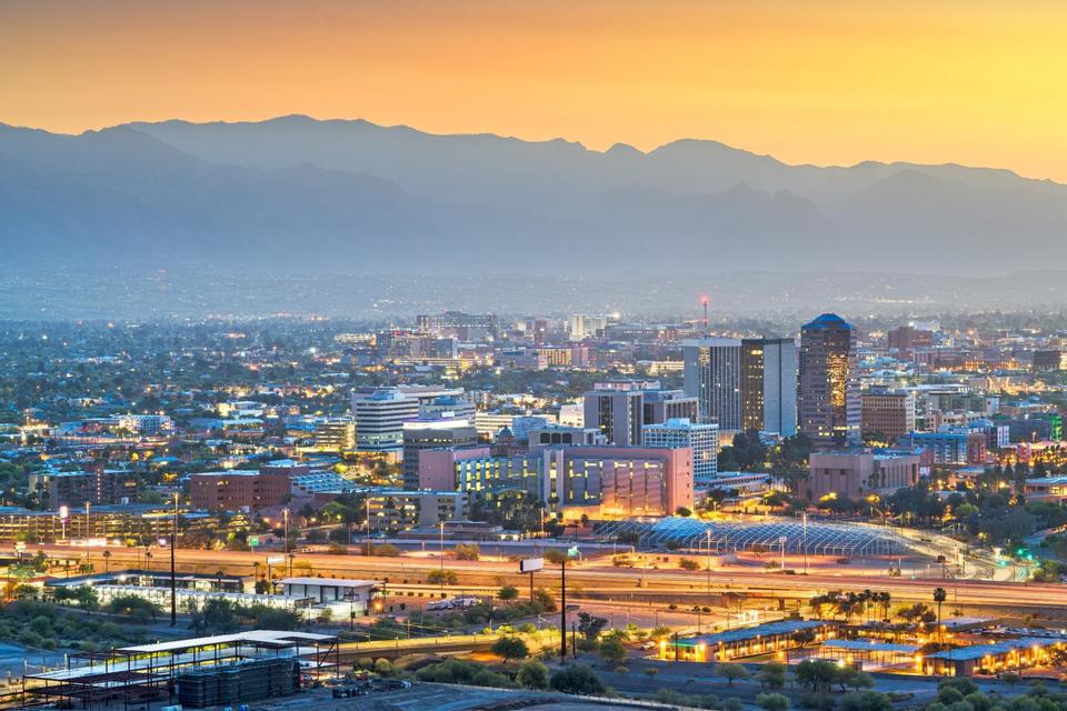 Tucson city skyline against a mountain backdrop during the dusk hour