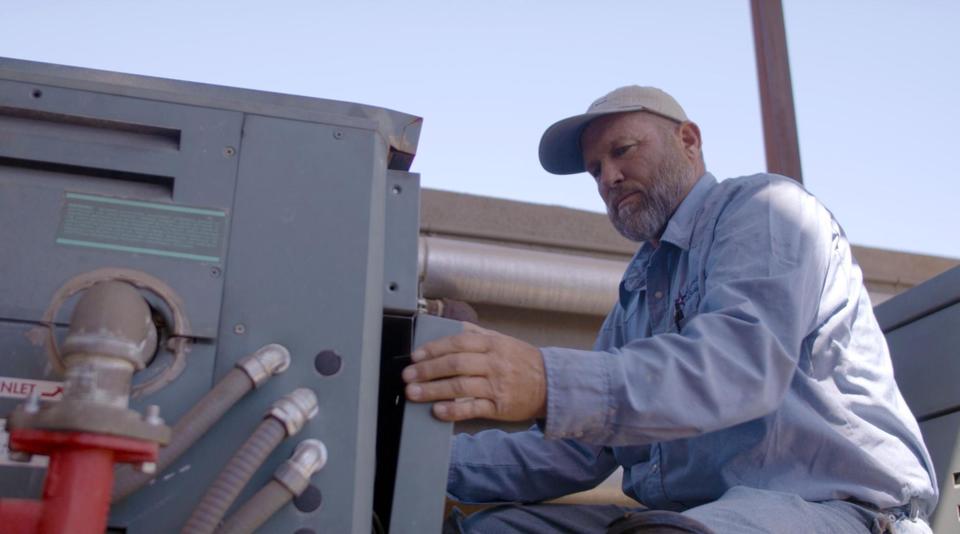 Advantage Air tech removing the front cover of an outdoor AC unit.