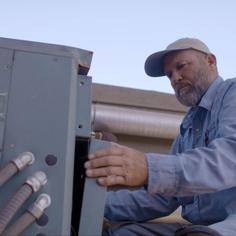 Advantage Air tech removing the front cover of an outdoor AC unit.