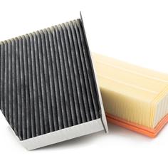 A small black air filter tilted on top of a cream air filter.