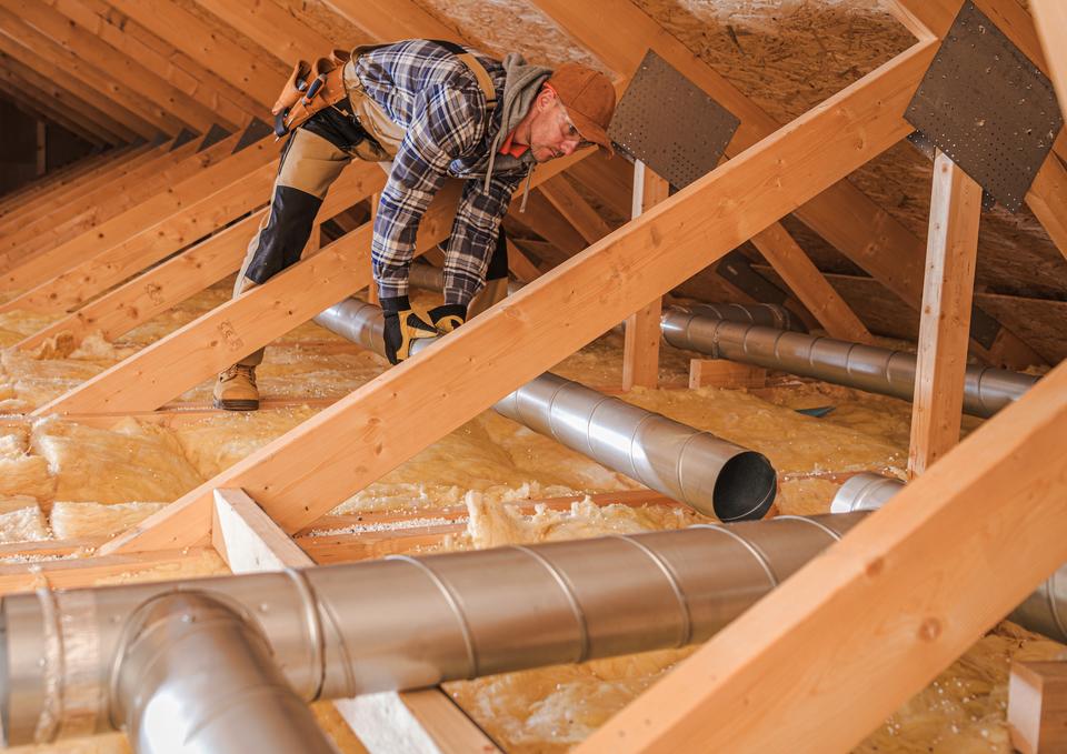 hvac technician installing new ductwork in a ceiling