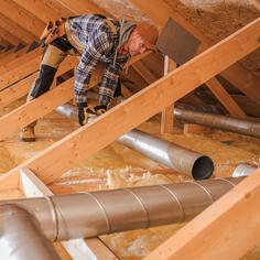 hvac technician installing new ductwork in a ceiling