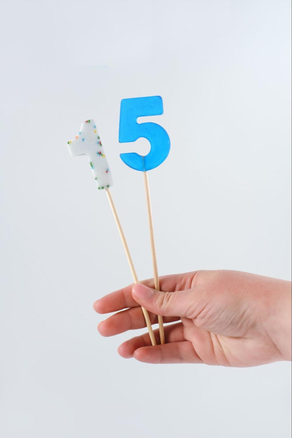 Hand holding out a '1' and a '5' on sticks to display 15