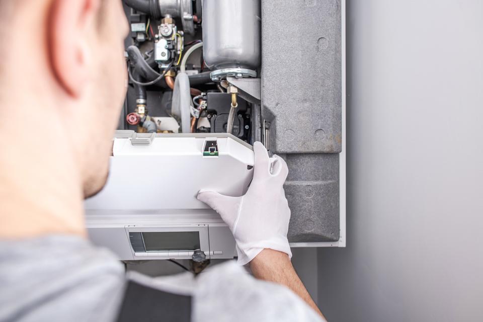 Professional HVAC technician performing a maintenance check up on a heater before winter starts